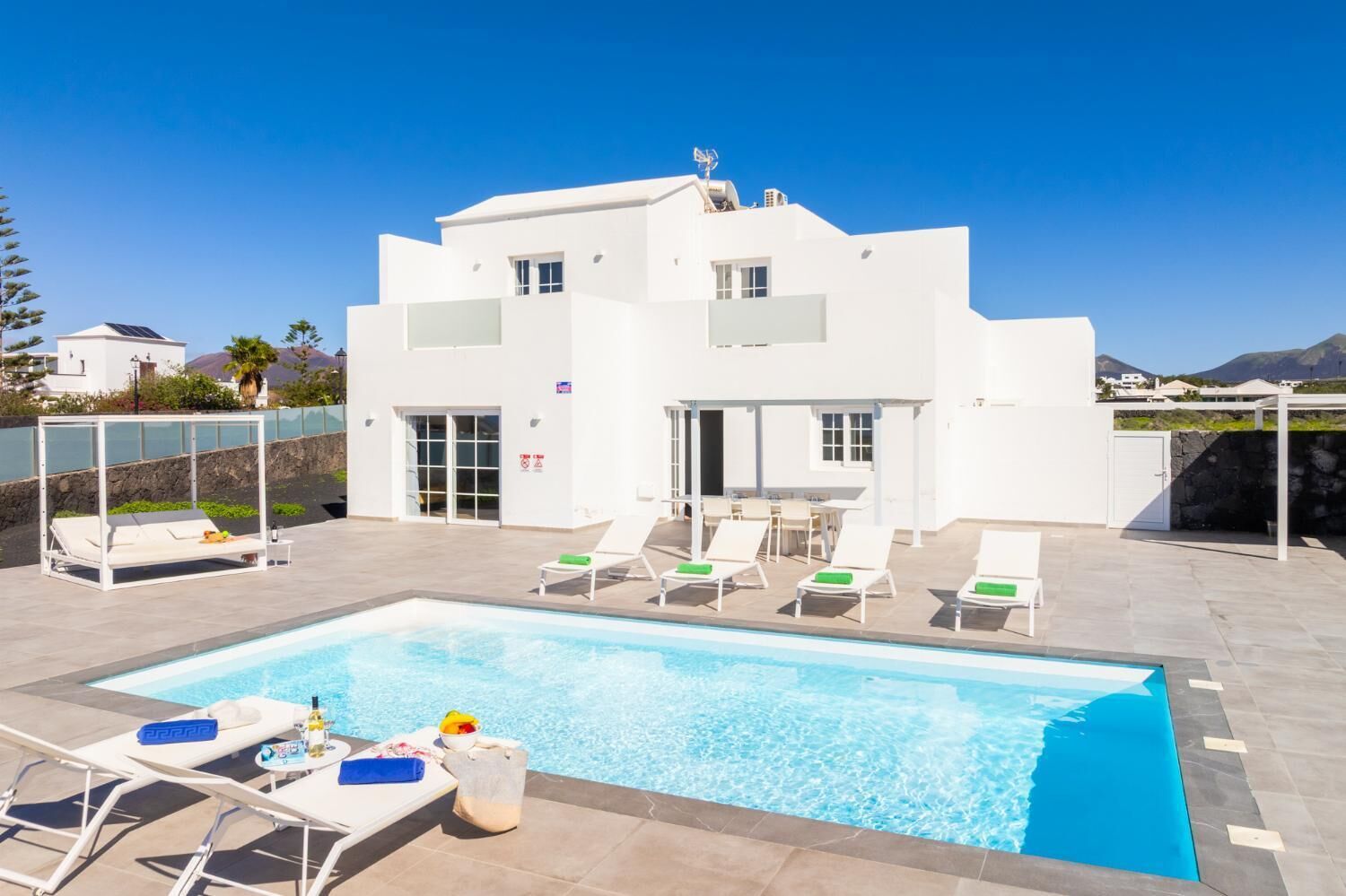 Un edificio moderno y blanco con piscina y tumbonas.
