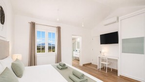 Ein Hotelzimmer mit einem großen Bett, einem Schreibtisch, einem Fernseher und Blick ins Freie.