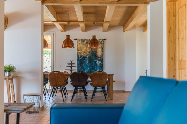 Un espace repas agrémenté de poutres en bois au plafond, d’un canapé bleu et d’une table avec des chaises.