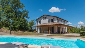 Ein zweistöckiges Haus mit einem Pool im Vordergrund.