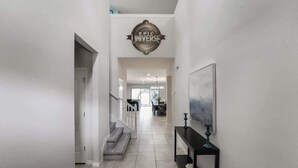 A modern hallway with a staircase, a decorative sign, and a framed artwork on the wall.