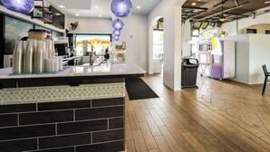 A modern cafe interior with a counter, stacked cups, and a vending machine.