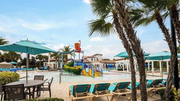 A pool area with lounge chairs, umbrellas, and a water slide.