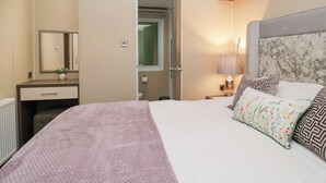 Una habitación de hotel con cama, mesita de noche, lámpara y espejo.