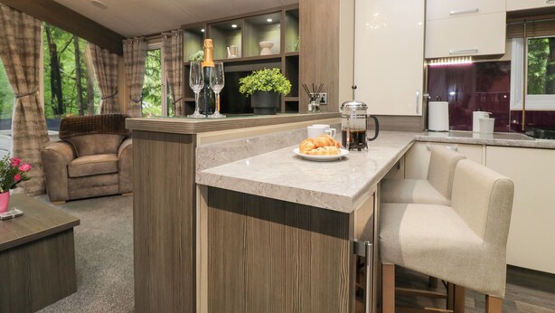 Una cocina moderna con una isla central, un comedor con sofá y vistas al exterior.