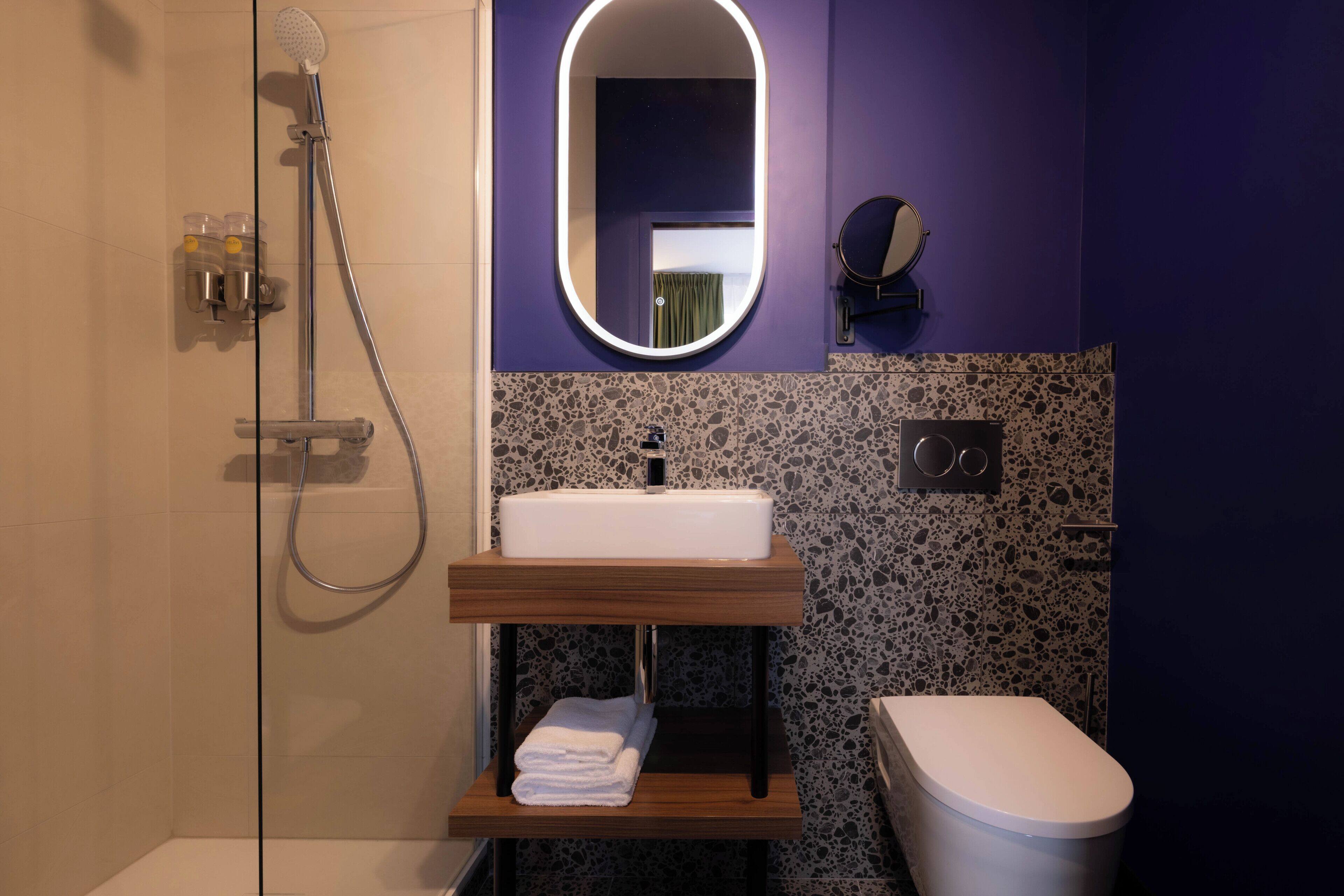 A bathroom with a shower, a sink, a toilet, a mirror, and a towel rack.