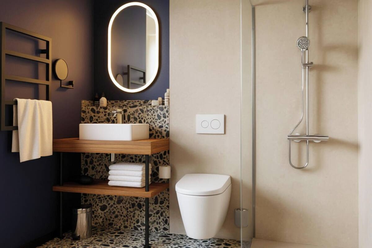 A modern bathroom with a freestanding sink, a toilet, a shower, and a mirror with a lighted frame.