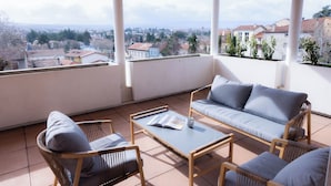 Uma área de estar coberta ao ar livre com vista para a paisagem urbana.
