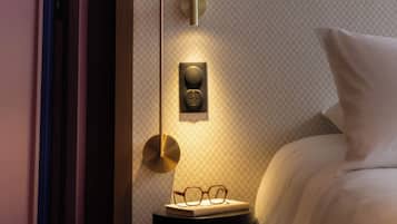 Un dormitorio con cama, mesita de noche y lámpara de pared.