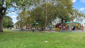 Um parque com equipamentos de playground, mesas para piquenique e bancos.