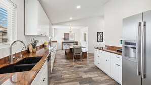 A modern kitchen with a wooden countertop, stainless steel appliances, and a herringbone floor pattern.