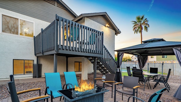 An outdoor patio with a fire pit, seating, and a covered area.