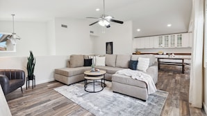 A modern living room with a sectional sofa, a round coffee table, and a ceiling fan.