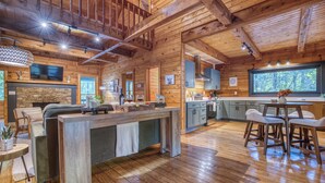 Interior espaçoso de uma cabana de registos, com uma grande área de refeições de madeira, cozinha e sala de estar.