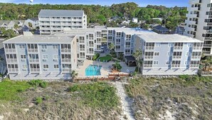 A multi-story hotel with a pool area and a beach view. - Palmwood Villas 101- Oceanfront 2BR/2BA- Pool (North Myrtle Beach)