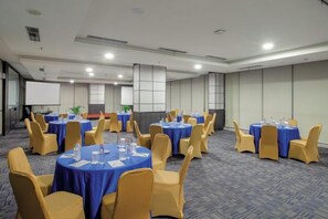 A conference room with round tables, chairs, and a projector screen.