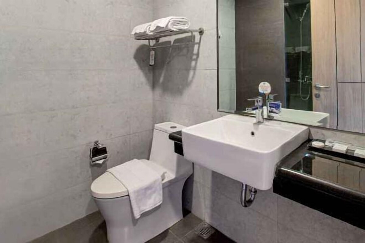 Un baño moderno con inodoro blanco, lavamanos y zona de ducha.