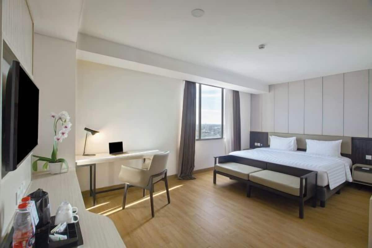 Ein Hotelzimmer mit Bett, Schreibtisch, Stuhl und einem Fenster mit Vorhängen.
