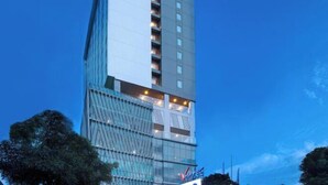 Ein modernes Hochhaus-Hotel mit Glasfassade, mehreren Balkonen und einer auffälligen Beschilderung am Fuß des Gebäudes.