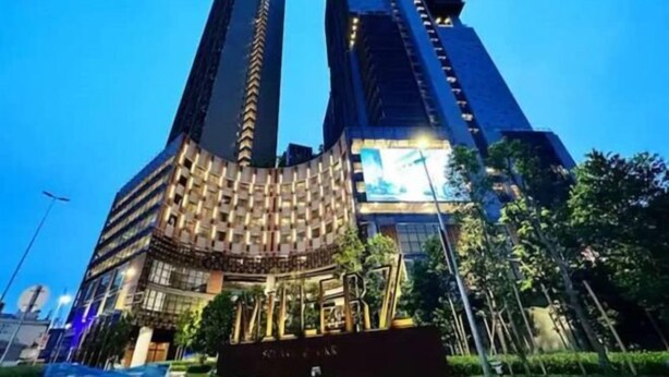 Un hotel moderno con una fachada curva distintiva y dos altos rascacielos al fondo.