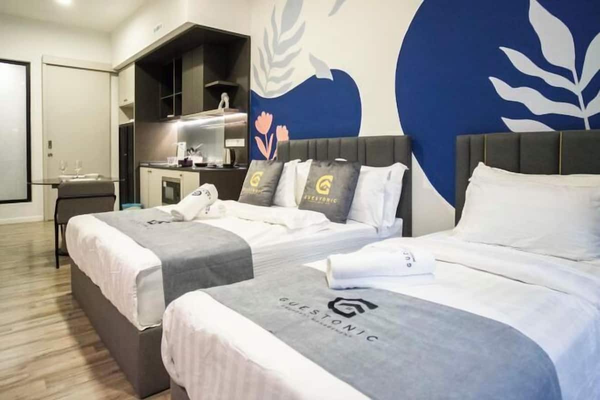 A hotel room with two beds, a kitchenette, and a large wall mural.