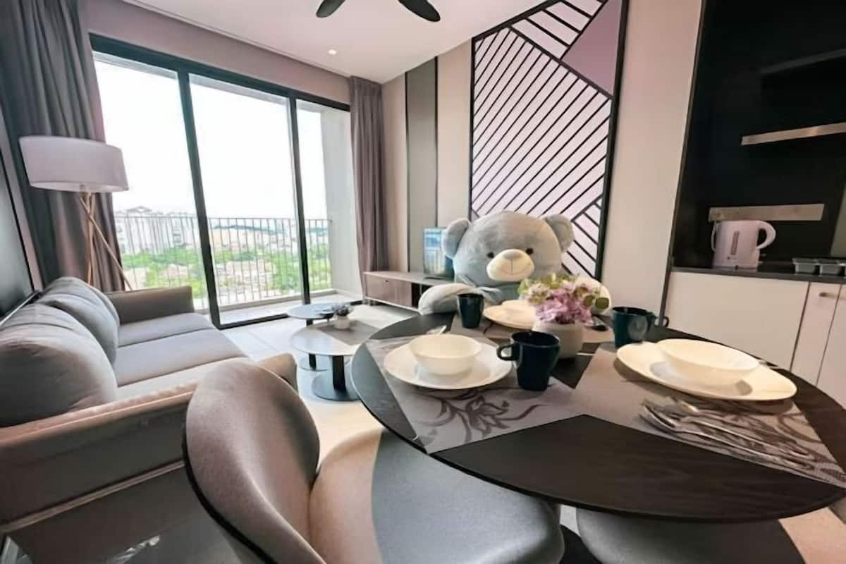 A modern living room with a sofa, a dining table set with plates, cups, and a teddy bear.