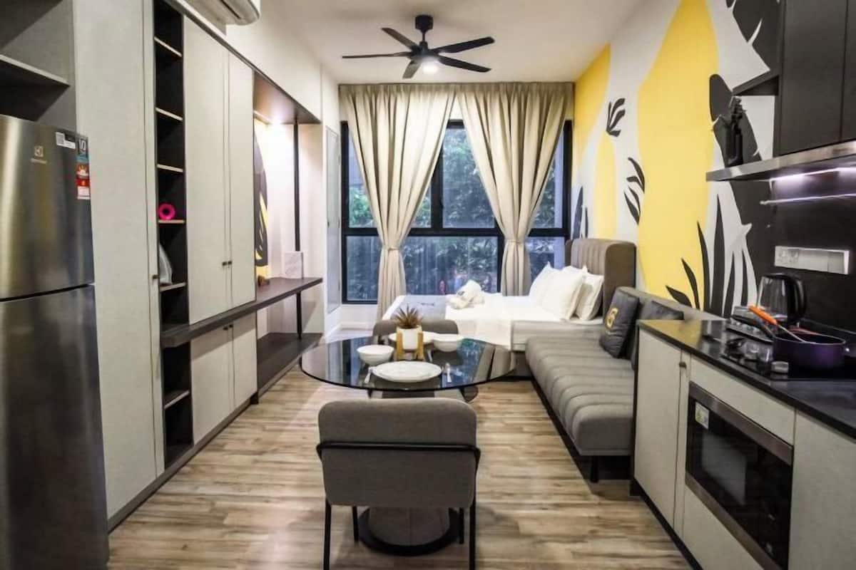 A compact living space with a kitchenette, a dining area with a glass table, a sofa, and a ceiling fan.