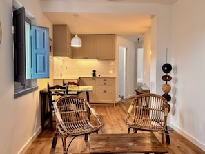 A kitchen with wooden cabinets, a dining table, two wicker chairs, and a hanging pendant light. - EL FORT D'ULLASTRET (Ullastret)