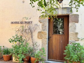 A stone building with a wooden door and potted plants. - EL FORT D'ULLASTRET (Ullastret)
