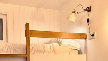 Una cama litera con escalera, un taburete pequeño y lámparas fijadas a la pared.