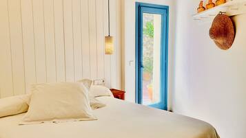 Une chambre à coucher comprenant un lit, une table de chevet, une porte donnant sur un espace extérieur et une étagère avec des objets décoratifs.