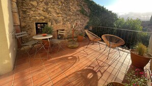Una terraza con paredes de piedra, una mesa con sillas y plantas en macetas.