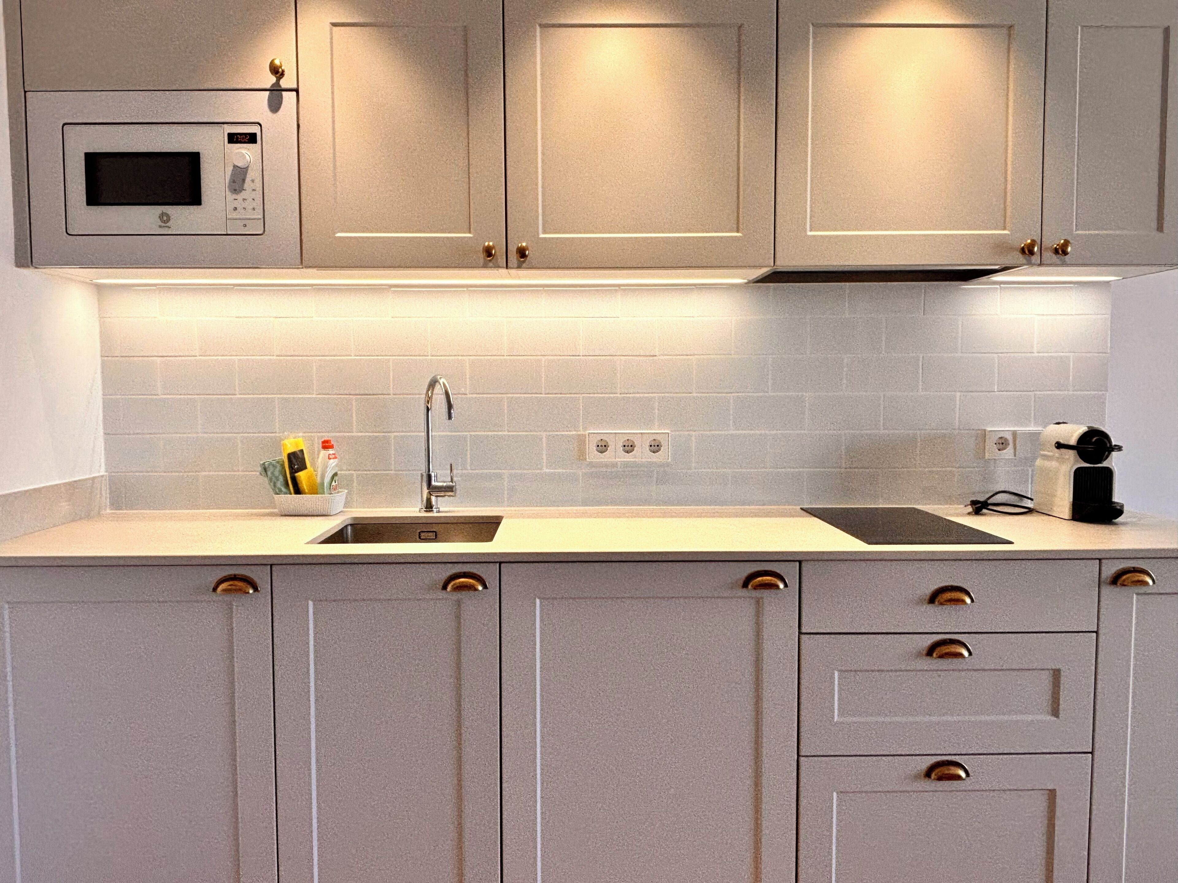 Una cocina con microondas, pileta y cajones.