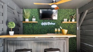 Eine moderne Küche mit grüner Wand, einer Holztresen und zwei Barhocker, sowie einem Deckenventilator.