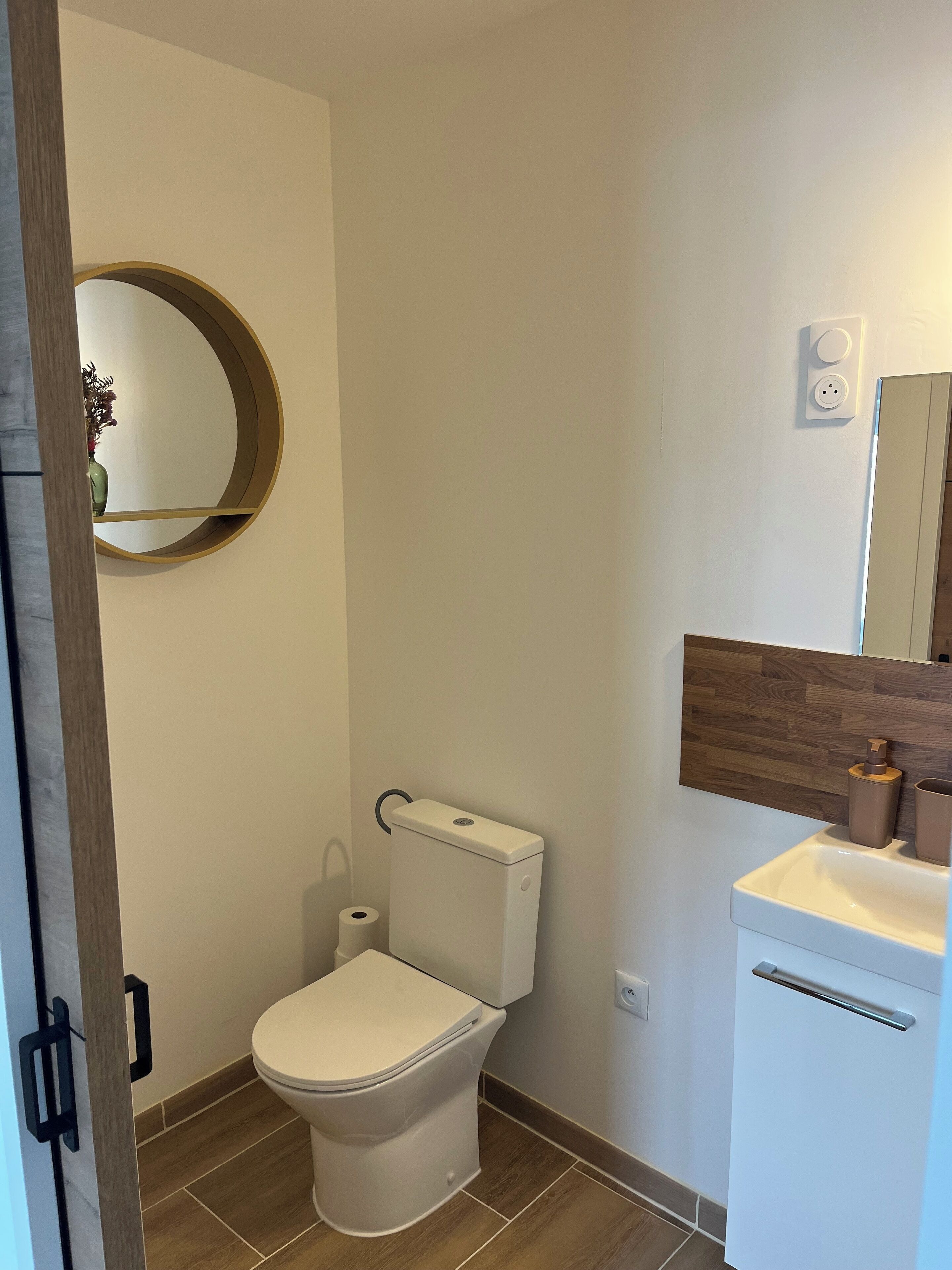 A modern bathroom with a toilet, a sink, and a mirror.