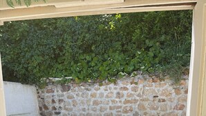 En uteplats med en mur av sten, en grå soffa och två fåtöljer av rotting.