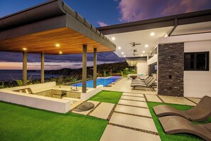 Ein moderner Außenbereich mit Pool, Liegestühlen und einer überdachten Terrasse.