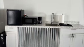 Eine Küche mit Mikrowelle, Kaffeemaschine und Spüle.