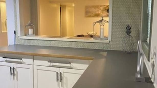 Cocina con armarios blancos, encimera de madera y salpicadero.