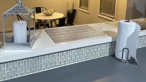 Un comedor con una mesa, sillas, un farol decorativo y una ventana con persianas.