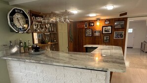 Eine Bar mit einer Marmorplatte, einer Uhr und verschiedenen Flaschen.