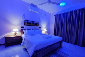 A bedroom with a bed, nightstands, a ceiling fan, and a window with curtains. - Villa Infinity Negombo (Negombo)