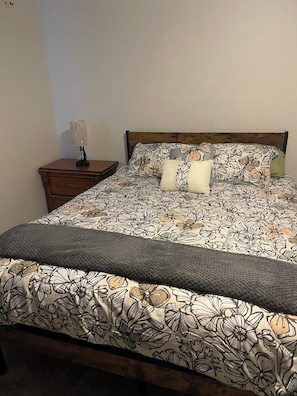 Un letto con biancheria da letto floreale, una lampada da comodino e una testiera in legno.