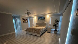 A bedroom with a bed, bedside tables, a ceiling fan, a window, and a door. - 4-bedroom, pool, fishing, games, BBQ, kayak and front water. (Cape Coral)