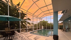 A pool area with lounge chairs and a covered section. - 4-bedroom, pool, fishing, games, BBQ, kayak and front water. (Cape Coral)