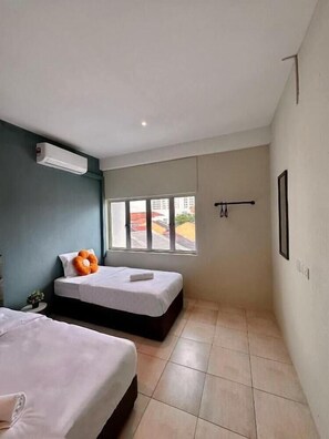 A small hotel room with two beds, a window, a wall-mounted air conditioner, and a view of the outside. - Swing & Pillows at Penang Road, Georgetown (Northeast Penang Island)