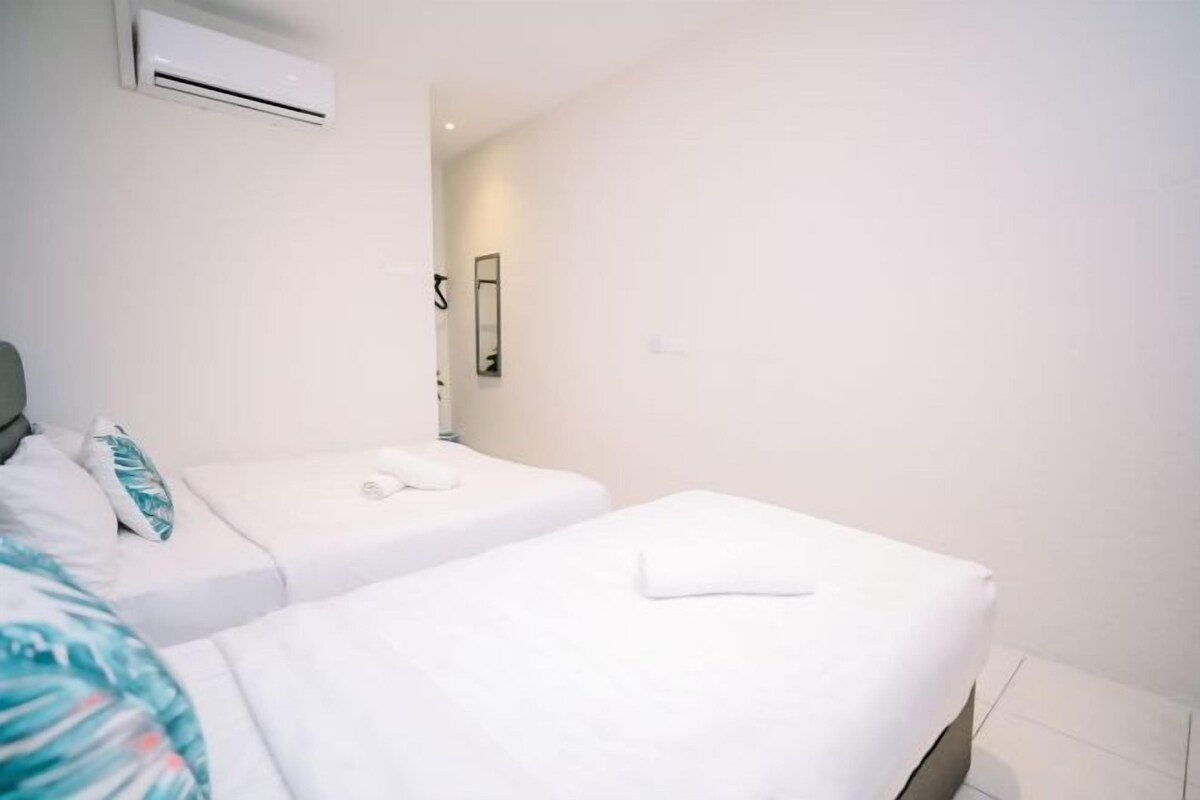A hotel room with two beds, a mirror, an air conditioning unit, and a small bathroom.