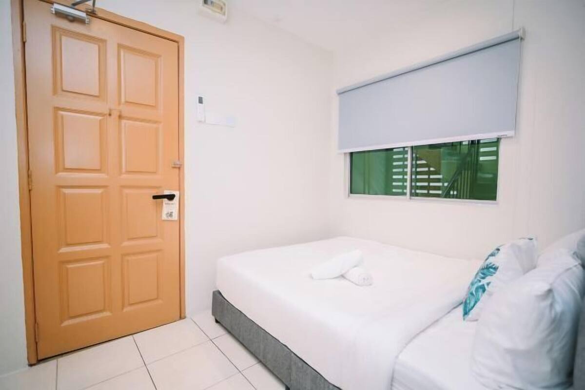 A room with a bed, a door, and a window with blinds.