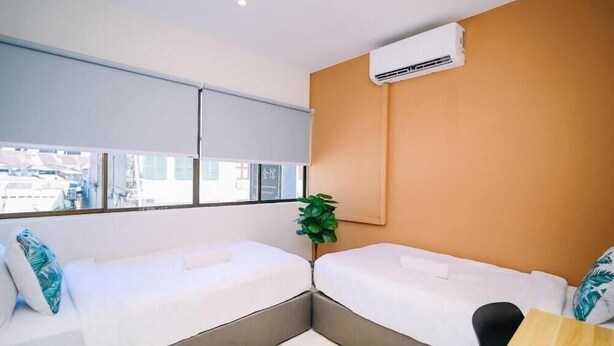 A hotel room with two beds, a window, an air conditioning unit, and a plant. - Swing & Pillows at Penang Road, Georgetown (Northeast Penang Island)