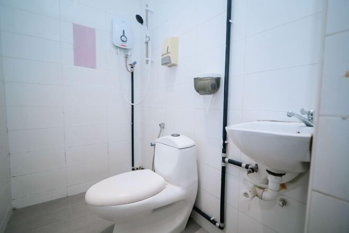 A white toilet, a sink, and a shower head in a bathroom with white tiles.
